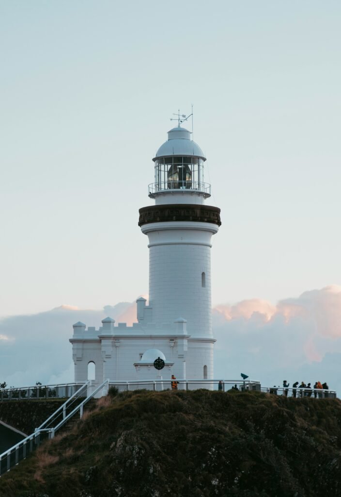 a white lighthouse with people standing on a hill