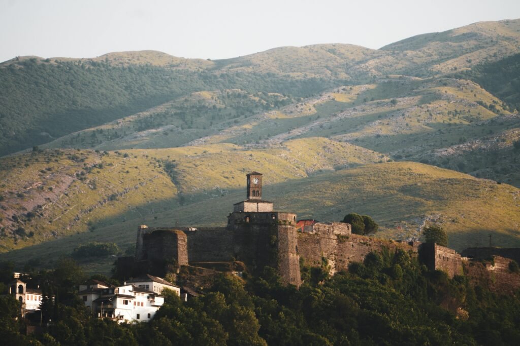 a stone castle with a clock tower on top of a hill